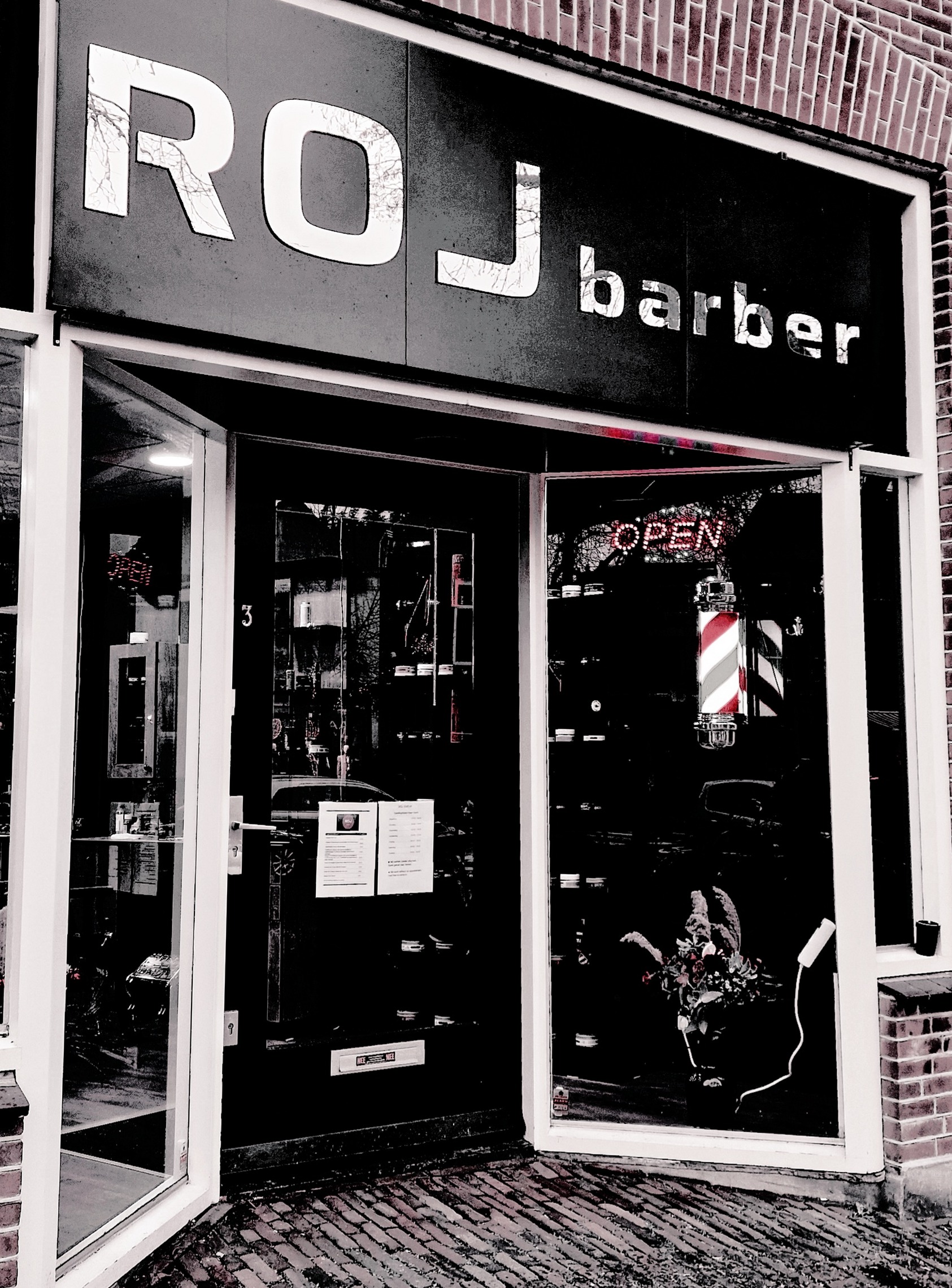 De gevel van Roj Barber aan de Gedempte Turfhaven: het bord ROJ barber, een kapperspaal en het OPEN-bord achter het raam