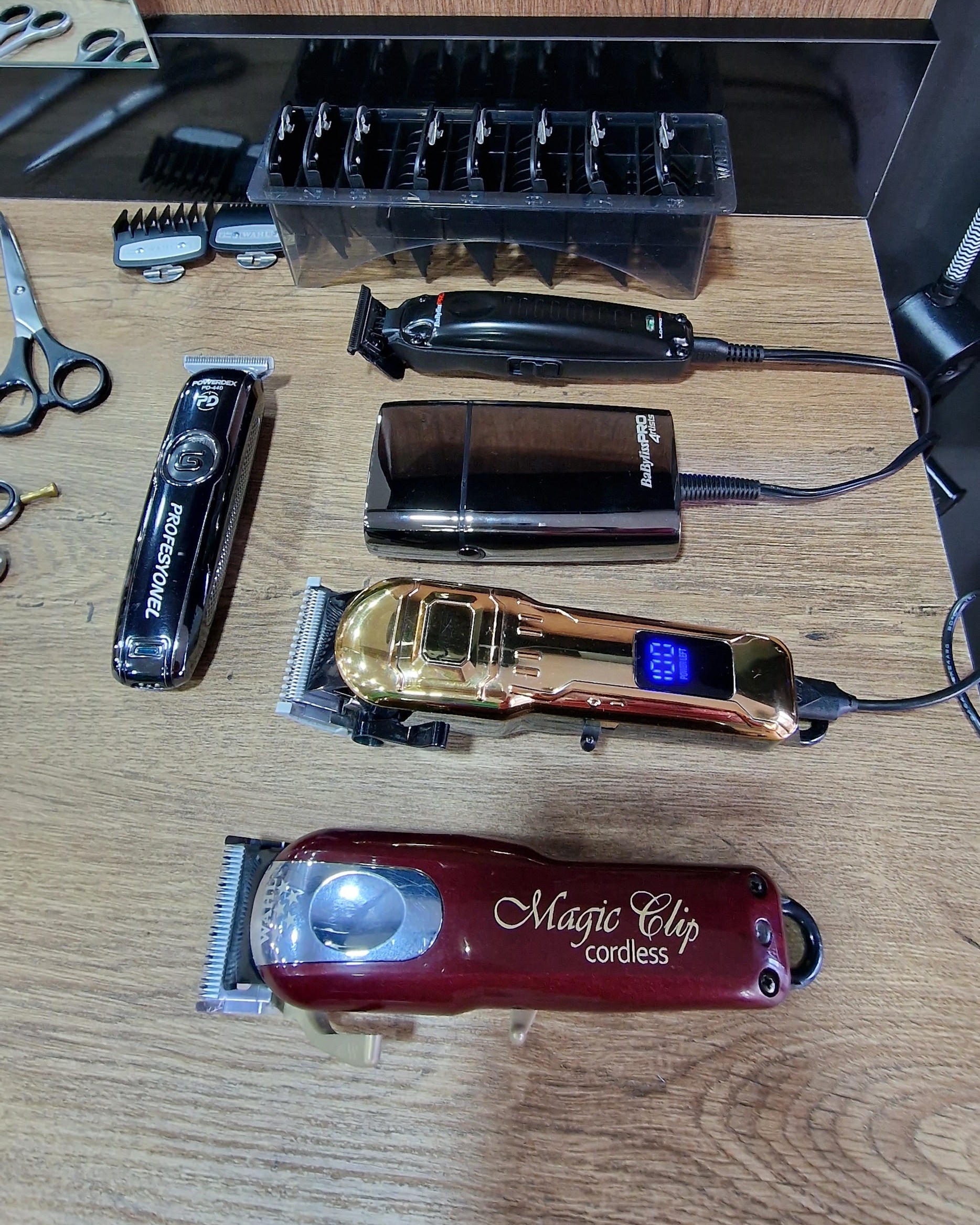 Tondeuses en trimmers op een eikenhouten toonbank, waaronder een rode Magic Clip